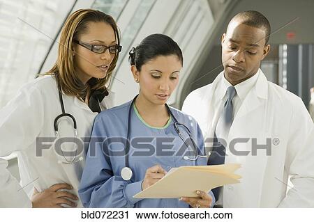 Multi-ethnic doctors and nurse reviewing medical chart View Large Photo Image Stock Image - Multi-ethnic doctors and nurse reviewing medical chart. Fotosearch