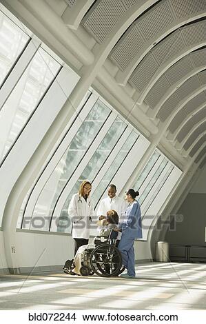 Picture - Multi-ethnic doctors and nurse with patient in wheelchair. Fotosearch