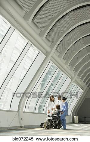 Stock Photography - Multi-ethnic doctors and nurse with patient in wheelchair. Fotosearch