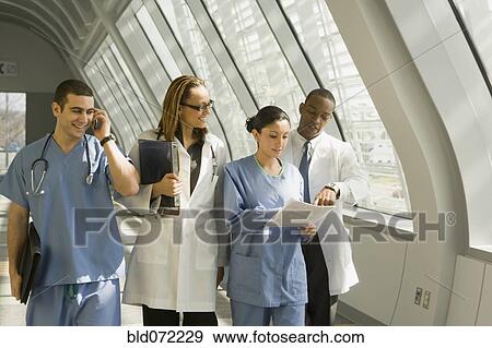 Stock Photo - Multi-ethnic doctors and nurses reviewing paperwork in corridor. Fotosearch