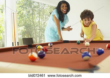 Stock Image - Multi-ethnic friends playing pool. Fotosearch