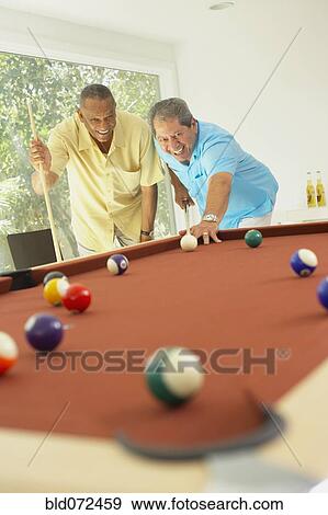 Stock Photo - Multi-ethnic friends playing pool. Fotosearch