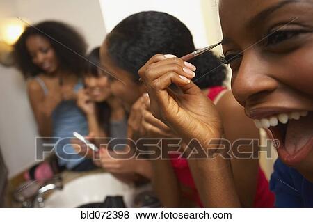 Stock Photo - Multi-ethnic group of friends applying makeup. Fotosearch