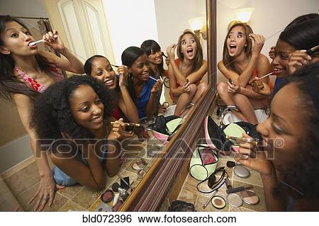 Stock Photograph - Multi-ethnic group of friends applying makeup. Fotosearch