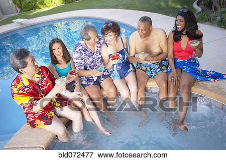 Stock Photo - Multi-ethnic group of friends enjoying pool party. Fotosearch