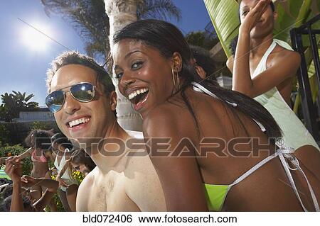 Stock Photograph - Multi-ethnic group of friends enjoying pool party. Fotosearch