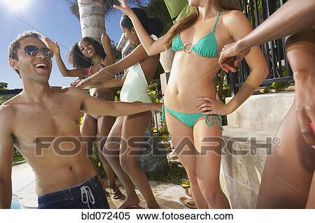 Stock Photography - Multi-ethnic group of friends enjoying pool party. Fotosearch