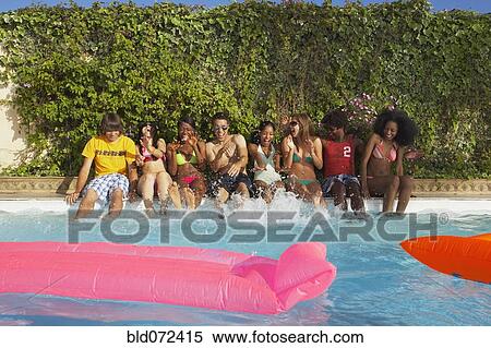 Stock Photography - Multi-ethnic group of friends enjoying pool party. Fotosearch