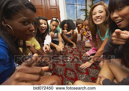 Stock Image - Multi-ethnic group of friends playing spin the bottle. Fotosearch