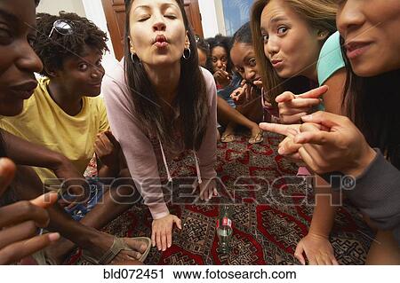 Stock Image - Multi-ethnic group of friends playing spin the bottle. Fotosearch