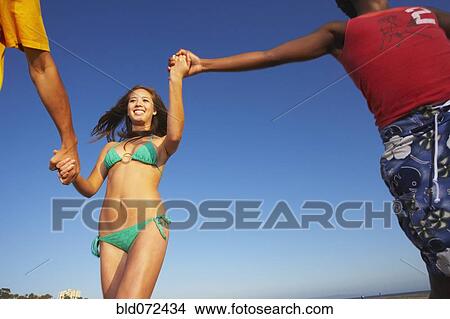 Picture - Multi-ethnic group of friends running on beach. Fotosearch