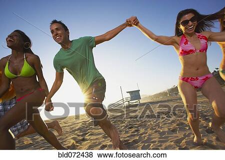 Stock Photo - Multi-ethnic group of friends running on beach. Fotosearch