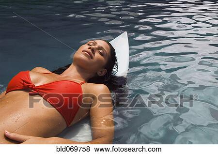 Stock Photo - Pacific Islander woman laying on surfboard in water. Fotosearch