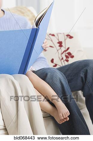 Parents reading to daughter on sofa View Large Photo Image Stock Image - Parents reading to daughter on sofa. Fotosearch