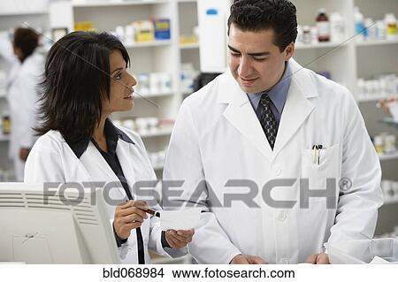 Picture - Pharmacists talking in pharmacy. Fotosearch