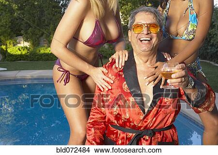 Playboy enjoying swimming pool with young girlfriends View Large Photo Image Picture - Playboy enjoying swimming pool with young girlfriends. Fotosearch