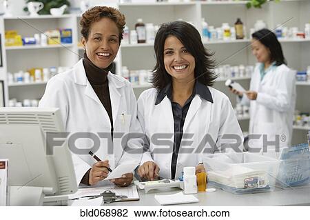 Stock Image - Portrait of female pharmacists in pharmacy. Fotosearch