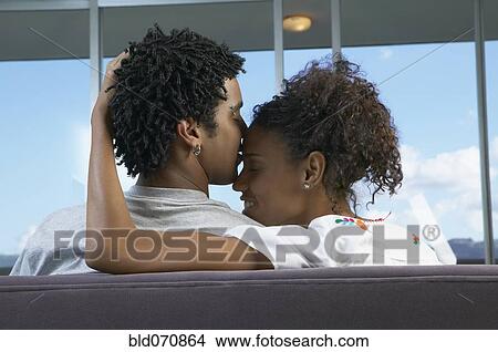 Rear view of African couple hugging on sofa View Large Photo Image Picture - Rear view of African couple hugging on sofa. Fotosearch