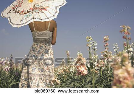 Stock Image - Rear view of Asian woman holding parasol. Fotosearch