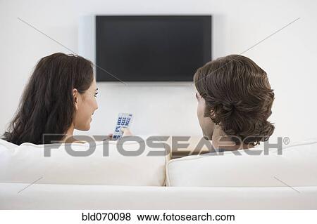 Rear view of couple watching television View Large Photo Image Stock Photo - Rear view of couple watching television. Fotosearch