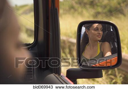 Stock Image - Reflection of Hispanic woman in side mirror of jeep. Fotosearch