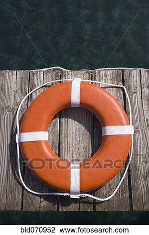 Stock Image - Round life preserver on wooden dock. Fotosearch