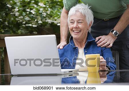 Senior couple looking at laptop outdoors View Large Photo Image Stock Image - Senior couple looking at laptop outdoors. Fotosearch