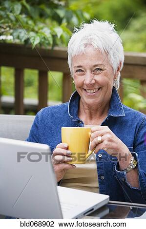Senior woman with coffee and laptop outdoors View Large Photo Image Stock Image - Senior woman with coffee and laptop outdoors. Fotosearch