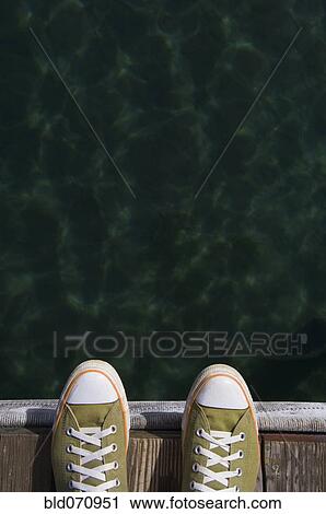 Stock Image - Sneakers on dock over water. Fotosearch
