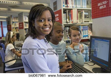 Stock Image - Teacher and students researching in library. Fotosearch