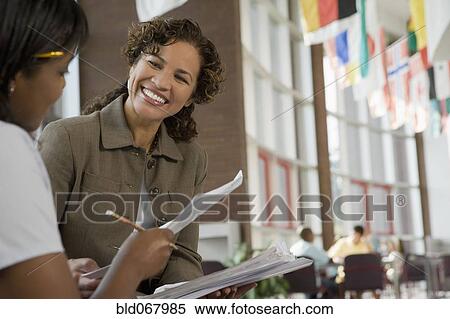 Stock Photography - Teacher giving paperwork to student. Fotosearch