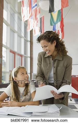Stock Image - Teacher helping student with homework. Fotosearch