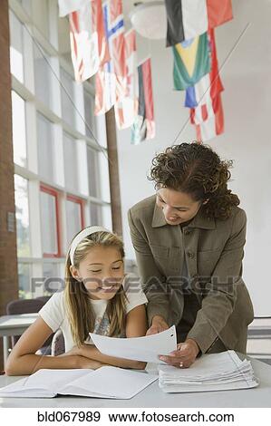 Stock Photo - Teacher helping student with homework. Fotosearch