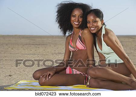 Stock Image - Twin sisters in bathing suits at beach. Fotosearch