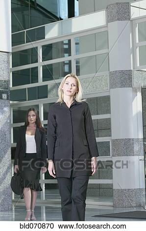 Stock Image - Two businesswomen walking out of building. Fotosearch