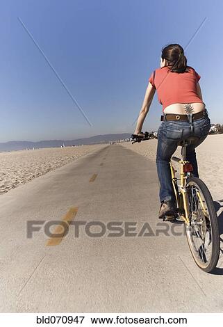 Stock Photo - Woman riding bicycle at beach. Fotosearch