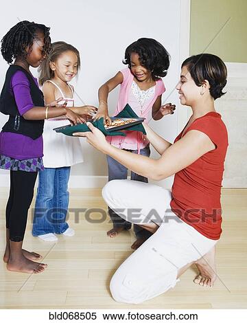 Stock Photography - Woman serving cookies to girls. Fotosearch