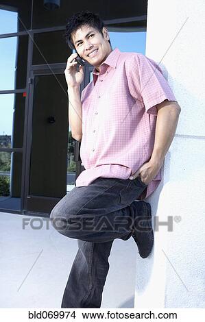 Picture - Young Asian man talking on cell phone. Fotosearch