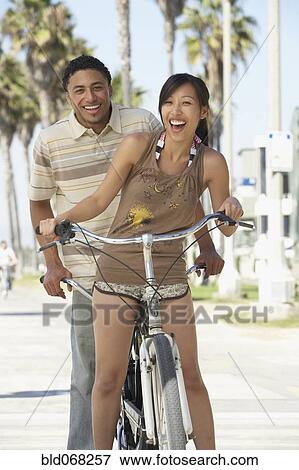 Stock Photo - Young couple standing with tandem bicycle. Fotosearch