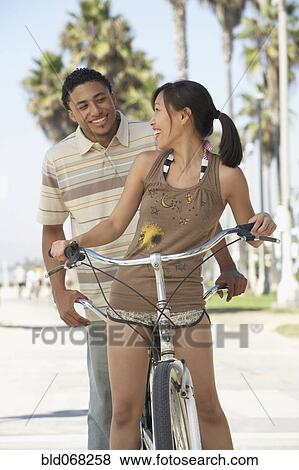 Stock Photo - Young couple standing with tandem bicycle. Fotosearch
