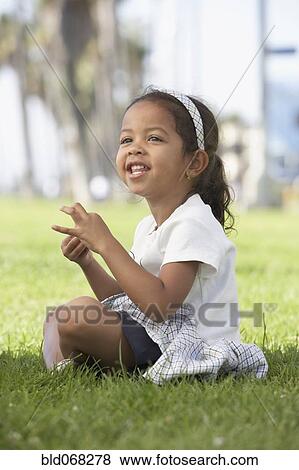 Young mixed race girl sitting cross-legged in grass View Large Photo Image Stock Photo - Young mixed race girl sitting cross-legged in grass. Fotosearch