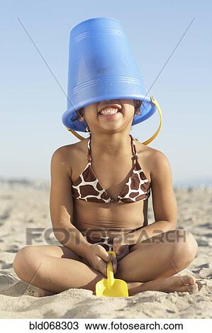 Young mixed race girl with bucket on head at beach View Large Photo Image Stock Image - Young mixed race girl with bucket on head at beach. Fotosearch