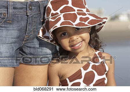 Stock Image - Young mixed race girl with mother at beach. Fotosearch