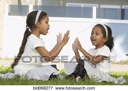 Young mixed race girls sitting and playing pat-a-cake View Large Photo Image Stock Photo - Young mixed race girls sitting and playing pat-a-cake. Fotosearch