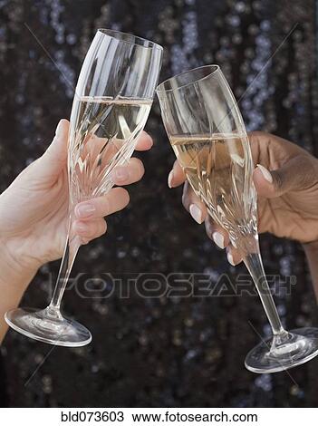 Stock Image - African and Caucasian woman toasting with champagne. Fotosearch