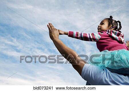 Stock Image - African father carrying daughter on shoulders. Fotosearch