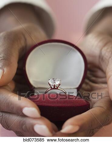 Stock Photography - African woman holding engagement ring in box. Fotosearch