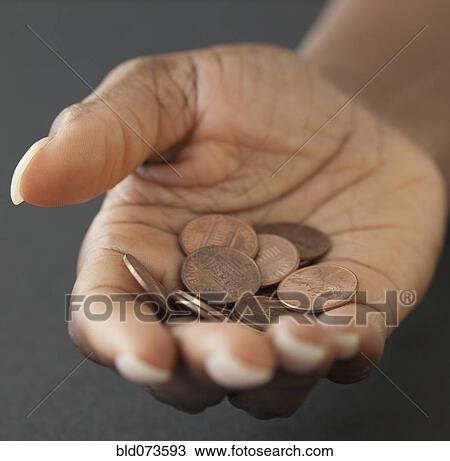 Stock Image - African woman holding handful of pennies. Fotosearch