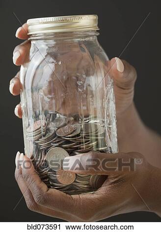 Stock Image - African woman holding jar of coins. Fotosearch