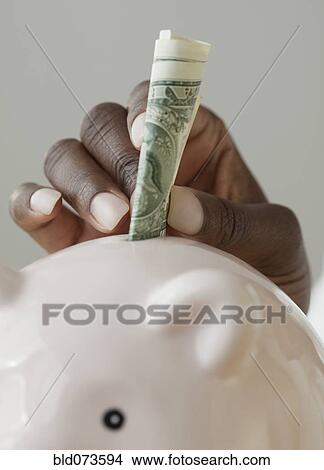 African woman putting money in piggy bank View Large Photo Image Picture - African woman putting money in piggy bank. Fotosearch
